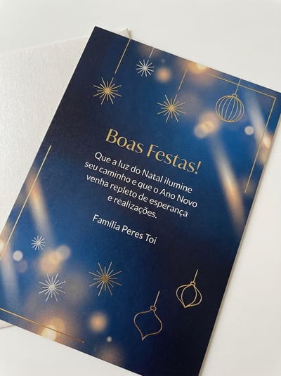 Blue festive holiday greeting card with gold snowflake lights, ornament accents, and elegant script names.
