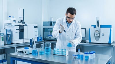 Scientist working with blue sample bottles and analytical instruments in a water quality testing laboratory.