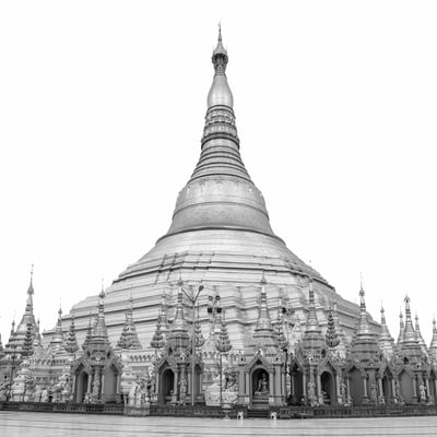 Black and white architectural photograph of Shwedagon Pagoda in Myanmar showing the central stupa, surrounding shrines, symmetrical details, and clean white background.