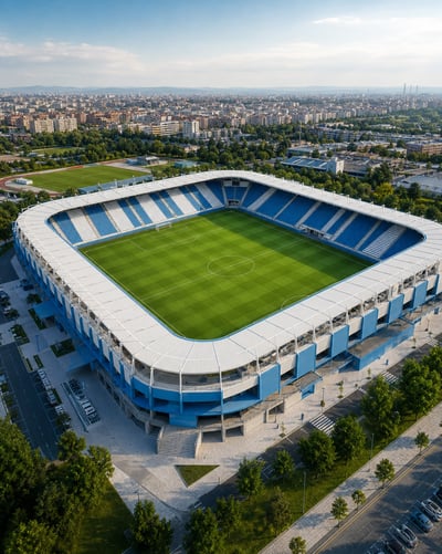 Oblique aerial view of a blue-and-white soccer stadium with a green pitch, lightweight white roof, and city surroundings